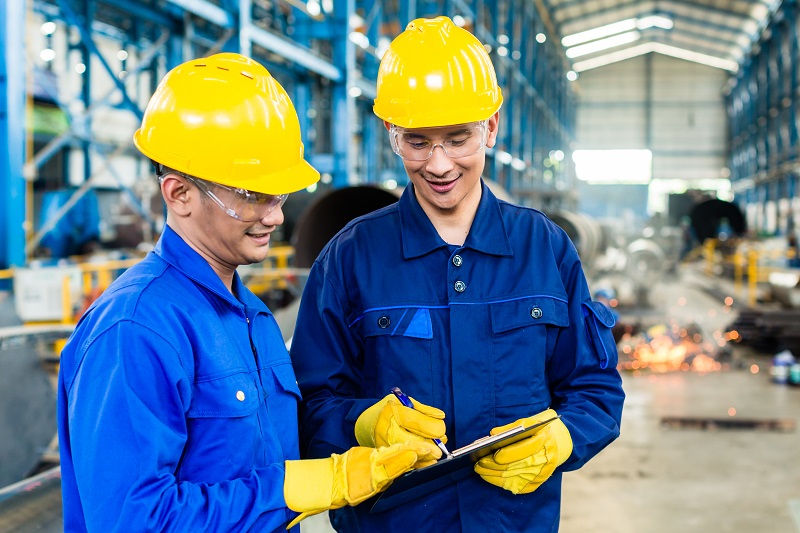 Two workers in production plant as team discussing safety.